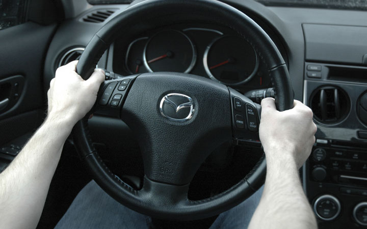 Holding a steering wheel at the “10 & 2” position
